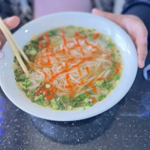 a person holding a bowl of soup