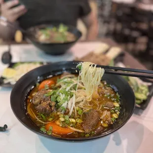 a bowl of soup with chopsticks