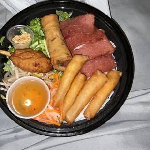 Bowl with sugarcane shrimp, egg rolls, and sausage
