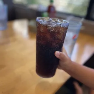 a person holding a glass of soda