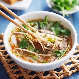 a bowl of soup with chopsticks