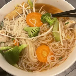 a bowl of soup with noodles, carrots and broccoli