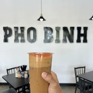 a hand holding a cup of iced coffee