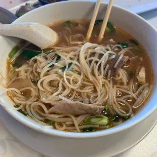 a bowl of noodle soup with chopsticks