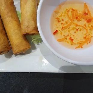a bowl of soup and three spring rolls