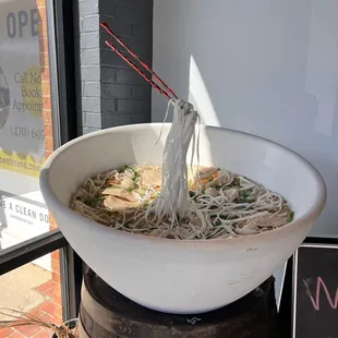 a bowl of noodles with chopsticks