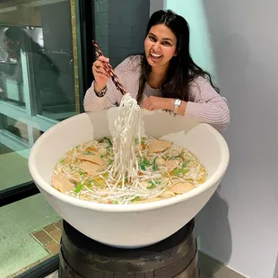 a woman eating a bowl of noodles