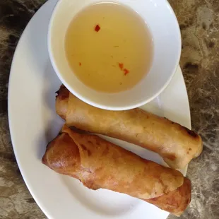 Two deep-fried egg rolls and dipping sauce