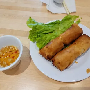 a plate of spring rolls and a bowl of dipping sauce