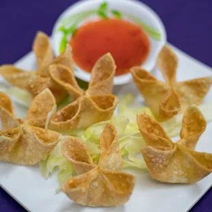 a plate of wontons with dipping sauce