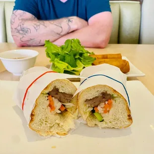 a man sitting at a table with a sandwich and salad