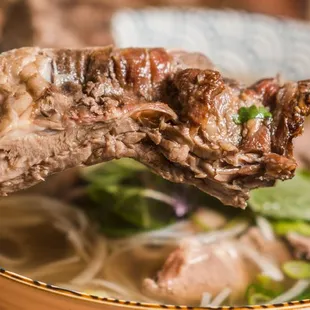 a person holding a chopstick over a bowl of soup