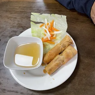 a plate of spring rolls and a bowl of dipping sauce