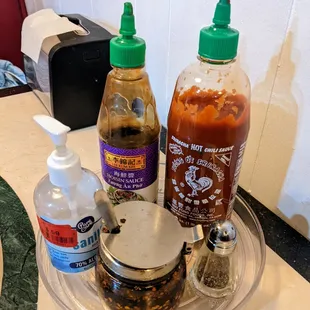 Table condiments include hoisin sauce, Sriracha, and red chili oil.