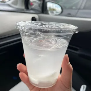 a hand holding a plastic cup filled with liquid