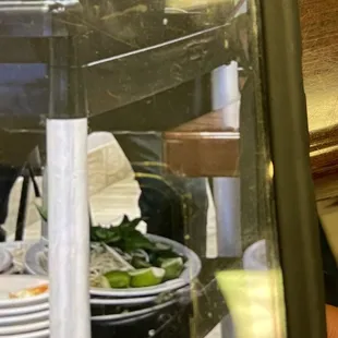 Trash scraped off the plates into the black bin on top; basil and bean sprouts stacked and saved below on the shelf. Gross!!!