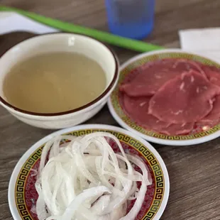 Pickled onions, rare steak on the side with a small bowl of hot broth