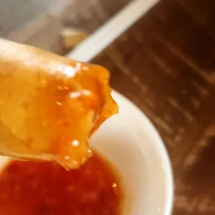 a person dipping sauce into a bowl