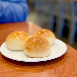 three buns on a plate on a table