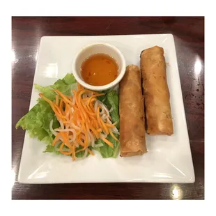 a plate of spring rolls and a bowl of dipping sauce