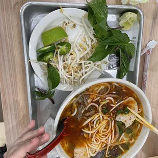 spicy noodles share a tray with additional ingredients provided on the side