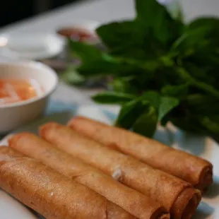 a plate of spring rolls and a bowl of dipping sauce