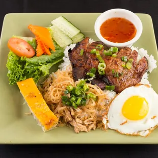 Rice platters with pork chop , shredded pork , quiche and sunny side up egg.