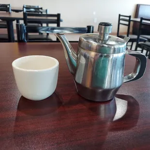 a coffee pot and a cup on a table