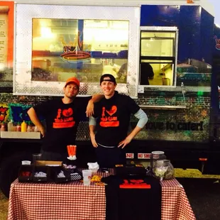 two men standing in front of a food truck