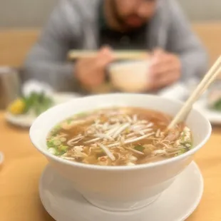 a man eating a bowl of soup with chopsticks