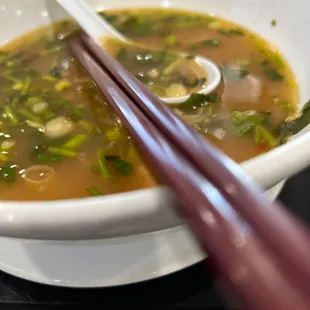 a bowl of soup with chopsticks