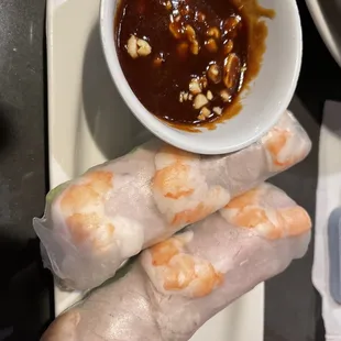 a bowl of dipping sauce and a plate of shrimp spring rolls