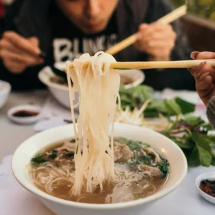a man eating noodles with chopsticks