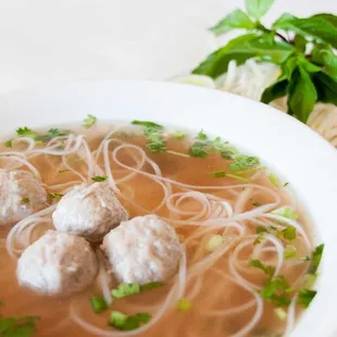 a bowl of soup with noodles and meatballs