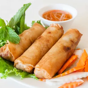 a plate of spring rolls and a bowl of dipping sauce
