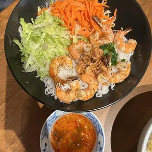 a plate of noodles, shrimp, carrots, and lettuce
