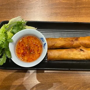 a bowl of dipping sauce and a plate of spring rolls
