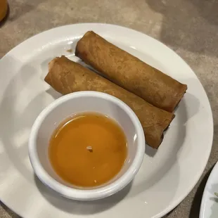 a plate of fried spring rolls with dipping sauce