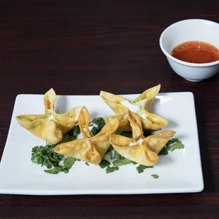 a plate of wontons with dipping sauce