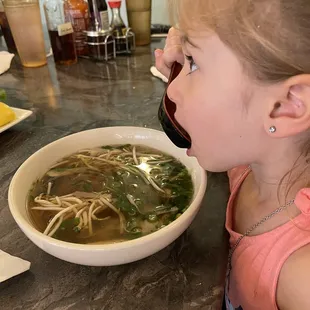  a little girl eating a bowl of soup