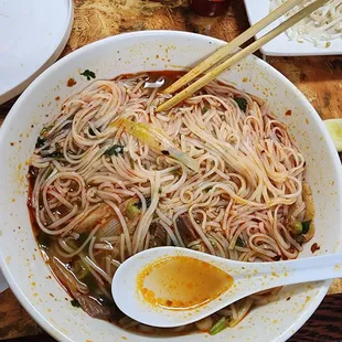 a bowl of noodles with chopsticks