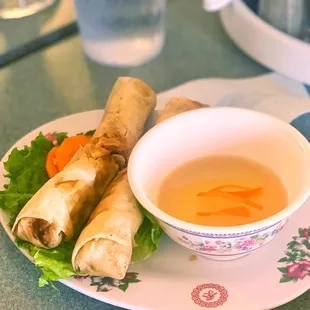a bowl of soup and a plate of spring rolls