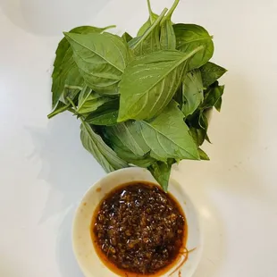 a bowl of sauce and a leaf of basil