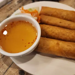 a plate of spring rolls with dipping sauce