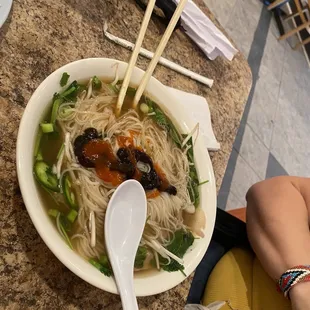 a bowl of soup with chopsticks