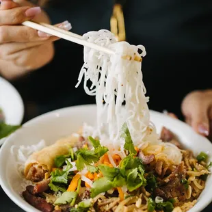 a person eating noodles with chopsticks