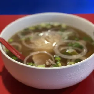 a bowl of soup with chopsticks