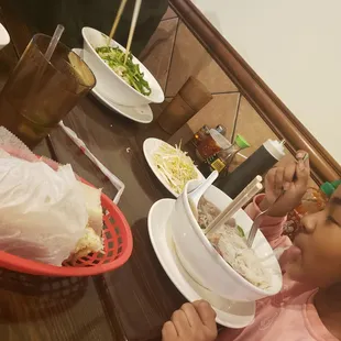 a little girl eating a bowl of noodles