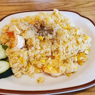 a plate of rice with shrimp and cucumbers