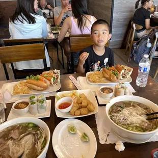 a boy sitting at a table with bowls of food
